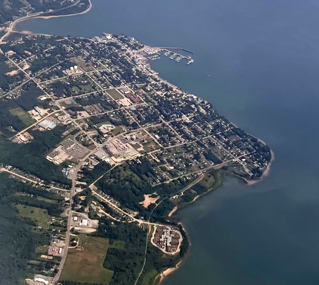 Aerial view of a coastal town with residential areas, roads, and a marina along the waterfront.